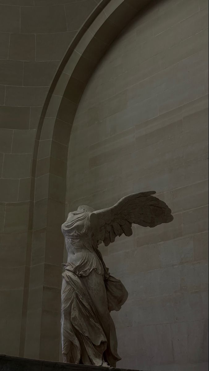 an angel statue in front of a stone wall with arched doorways and arches around it