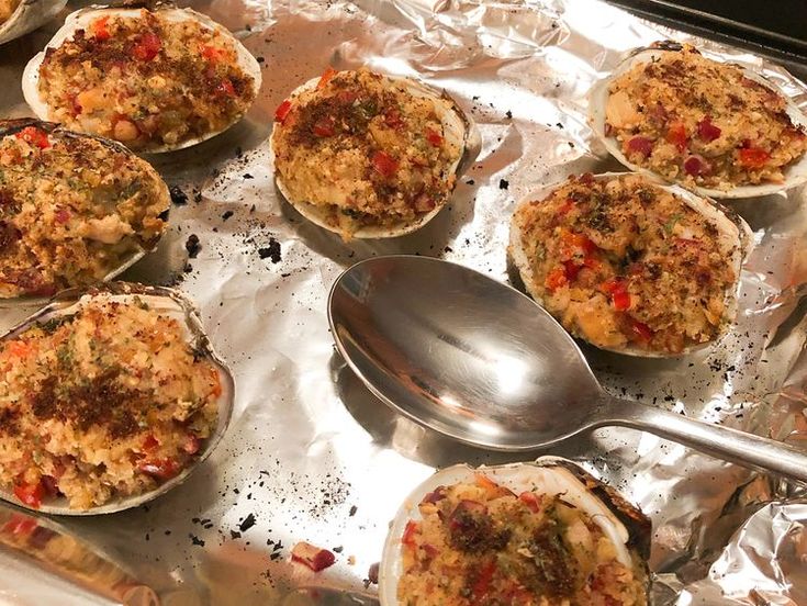 several baked food items on aluminum foil with spoons next to them, ready to be eaten