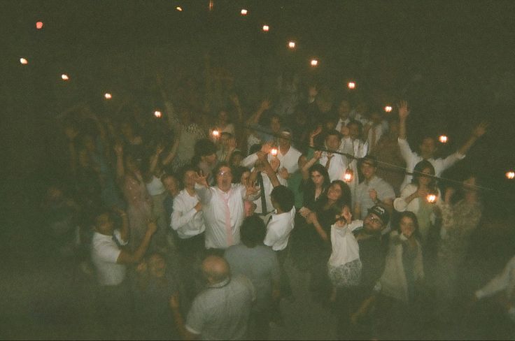 a group of people holding candles in their hands and standing around each other at night