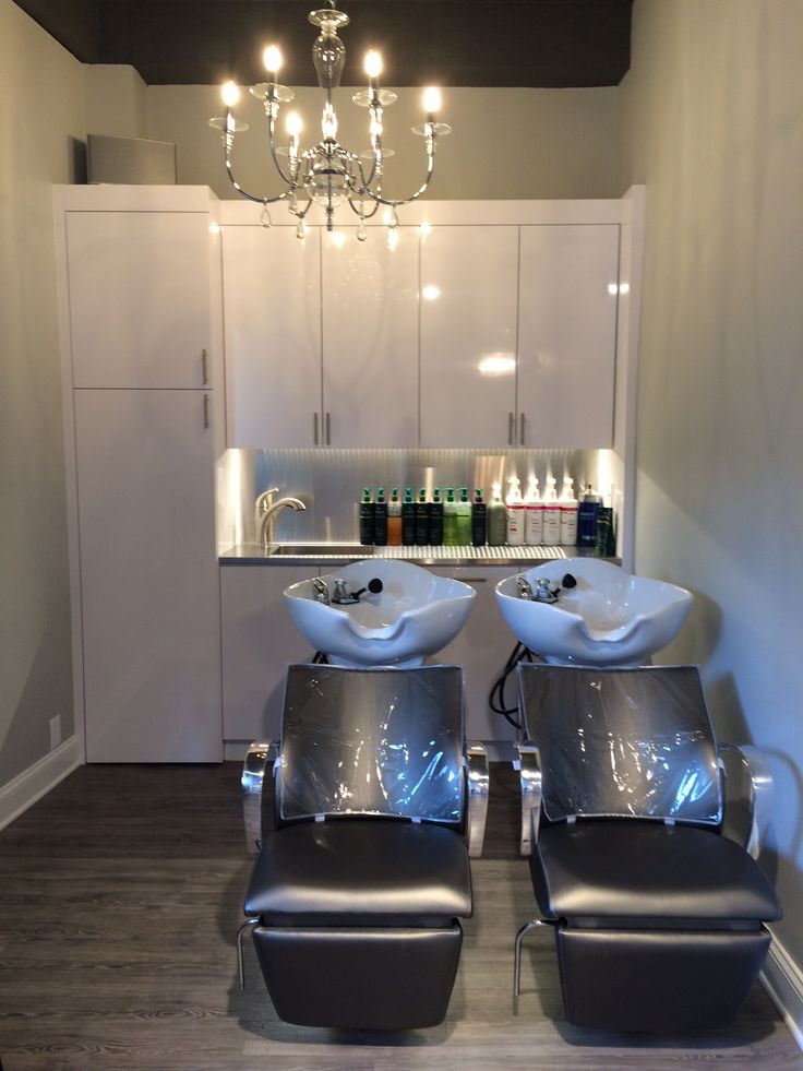 two white sinks sitting next to each other on top of a wooden floor under a chandelier