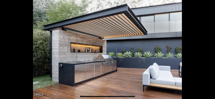 an outdoor kitchen and living room with wood flooring, patio furniture and grill area