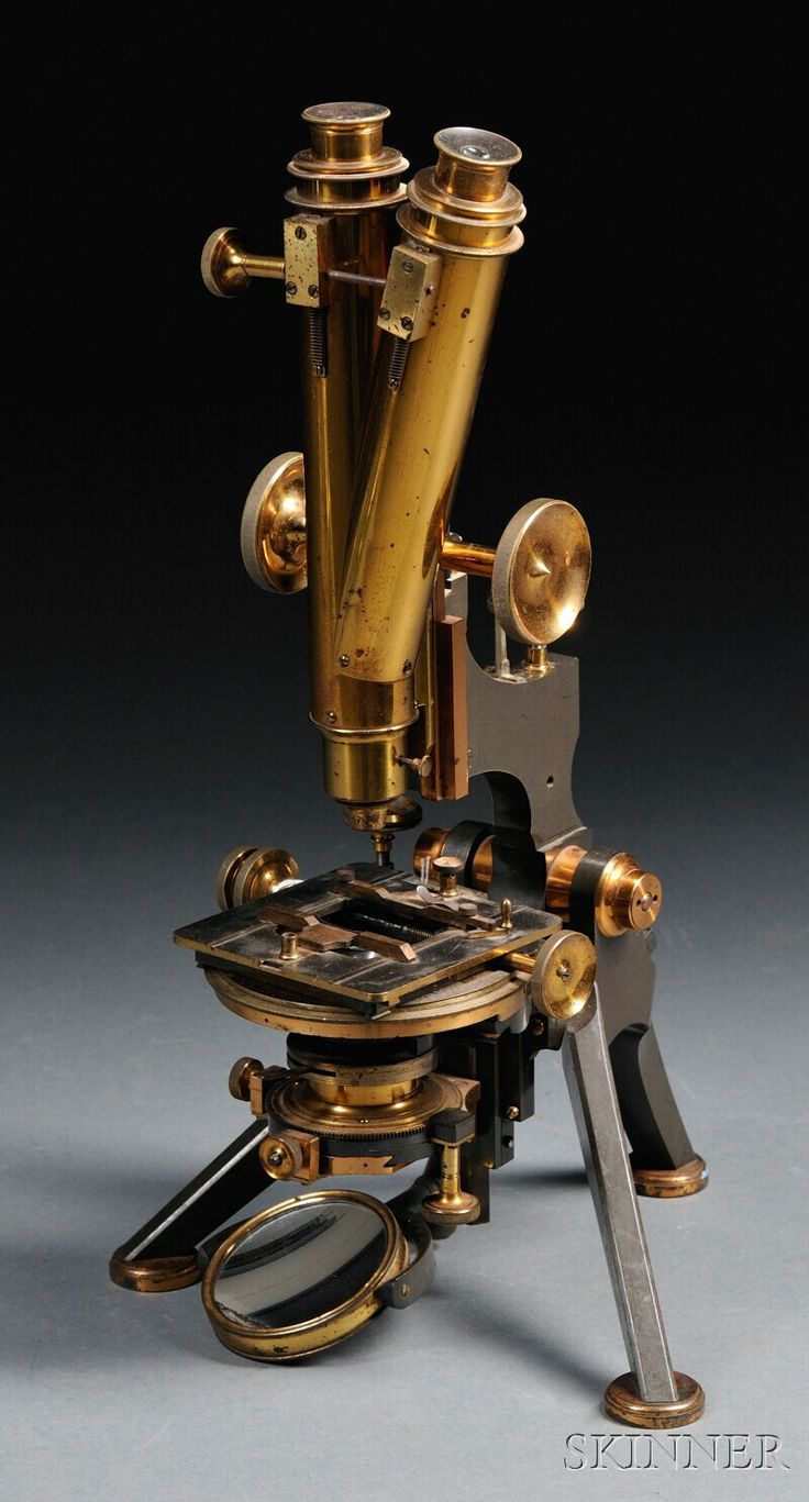 an antique microscope is shown on a gray surface with gold trimmings and two magnifying glasses