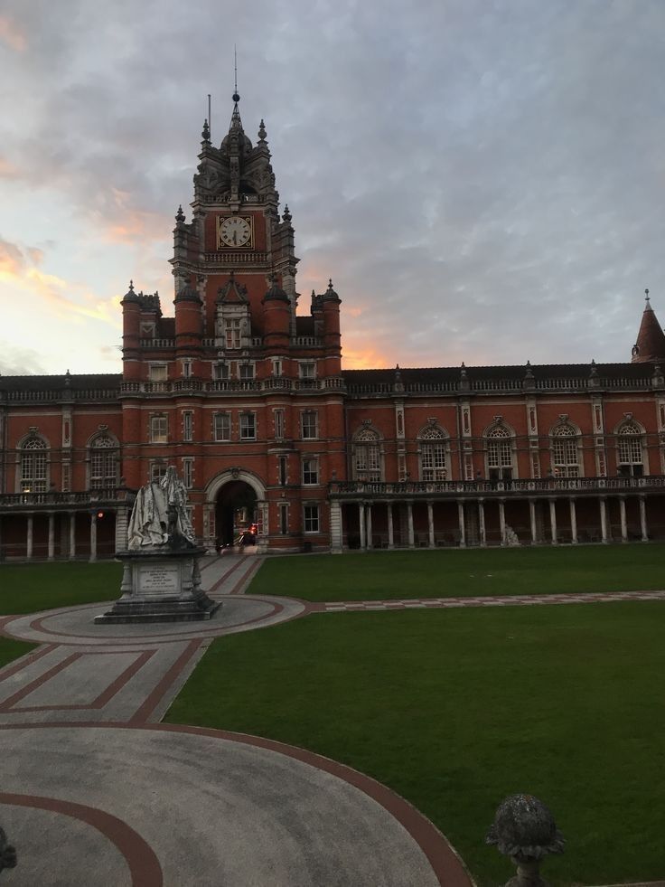 a large building with a clock on the tower and a statue in front of it