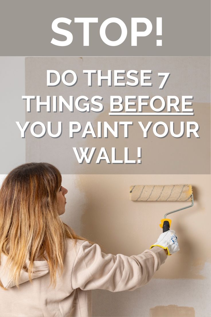 a woman is painting the wall with a paint roller