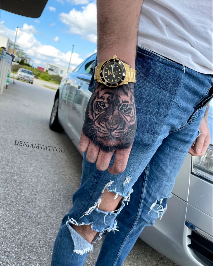 a man's hand with a tiger tattoo on it, next to a car