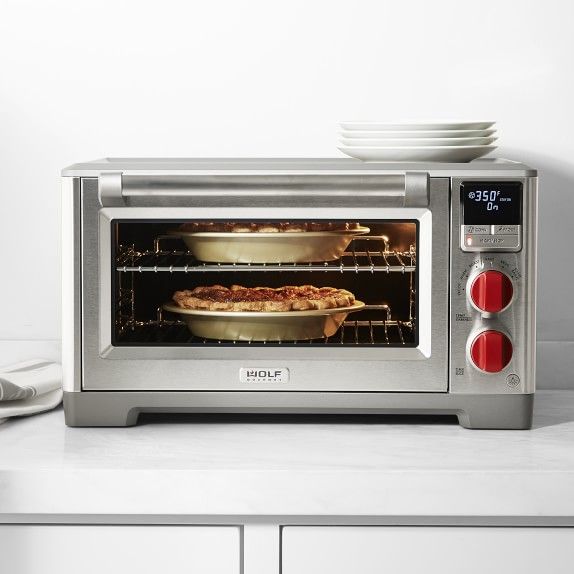 a toaster oven sitting on top of a counter with pizza in it's pans