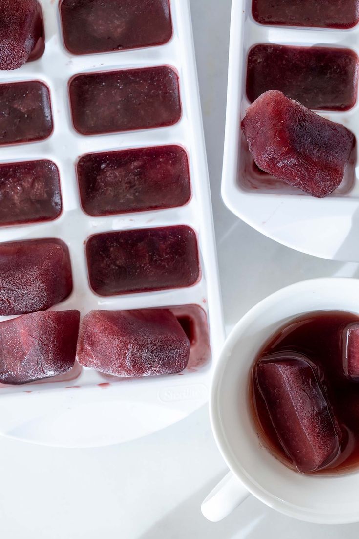 two white trays filled with ice cubes sitting next to each other on top of a table