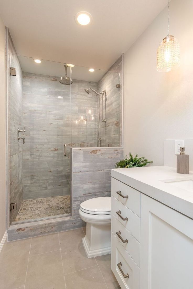 a bathroom with a walk in shower next to a white toilet and sink under two lights