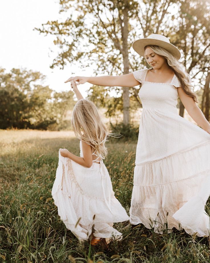 mother and daughter playing in the grass at sunset