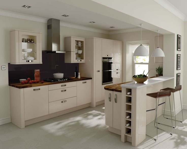 a modern kitchen with an island and bar stools in the center, surrounded by white cabinets