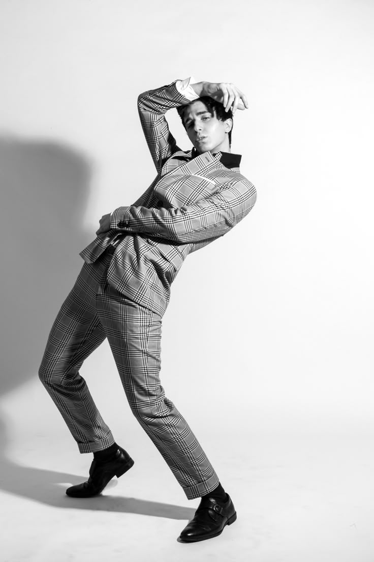 a man in a suit and tie poses for a black and white photo with his hands on his head