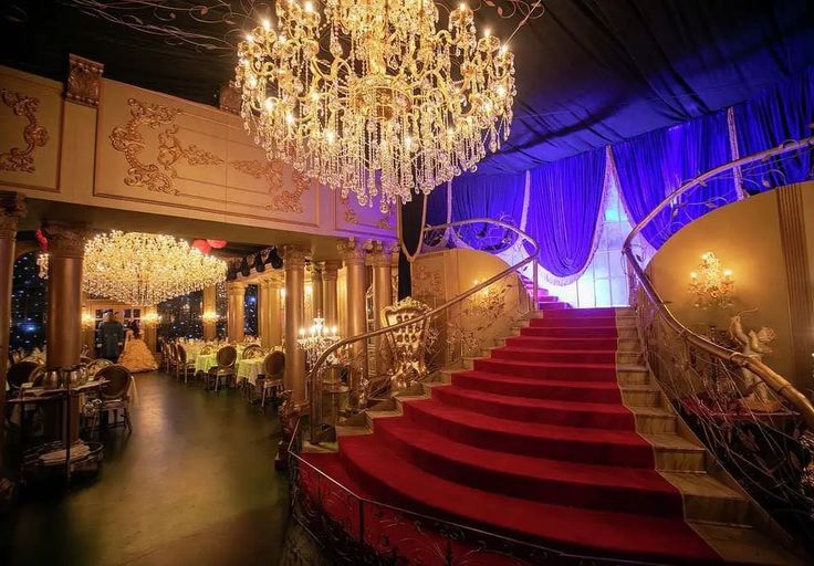 an elaborate staircase with chandelier and red carpeted stairs in a fancy setting