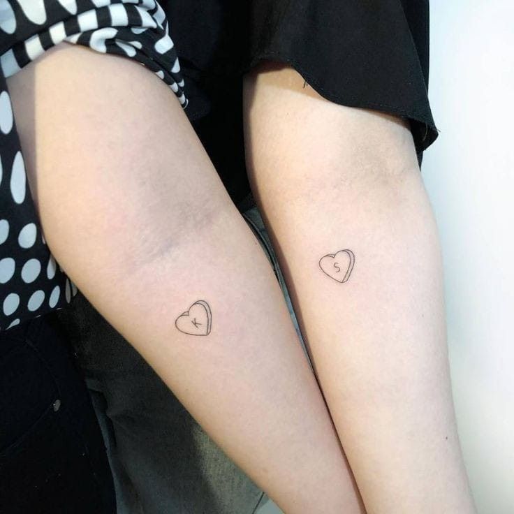 two people with matching tattoos on their legs, one is holding the other's leg