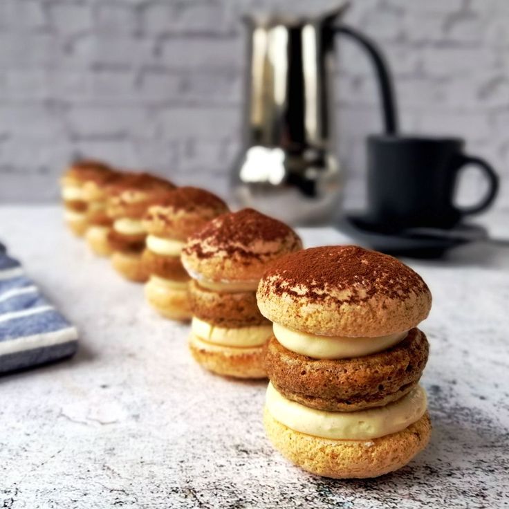 there are many donuts lined up on the counter next to a coffee cup and tea pot