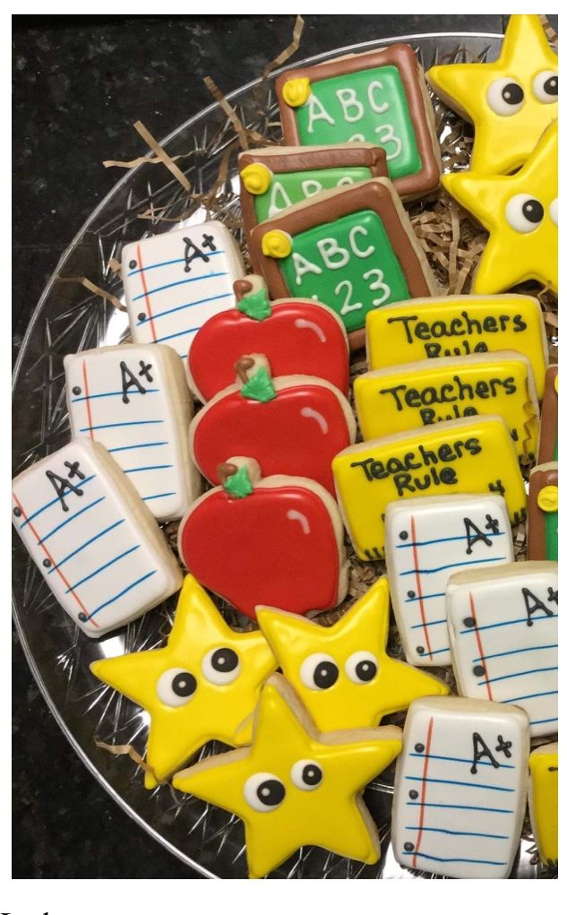 some cookies that are on a plate with writing paper and school supplies in the background