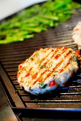 two hamburger patties cooking on an outdoor grill