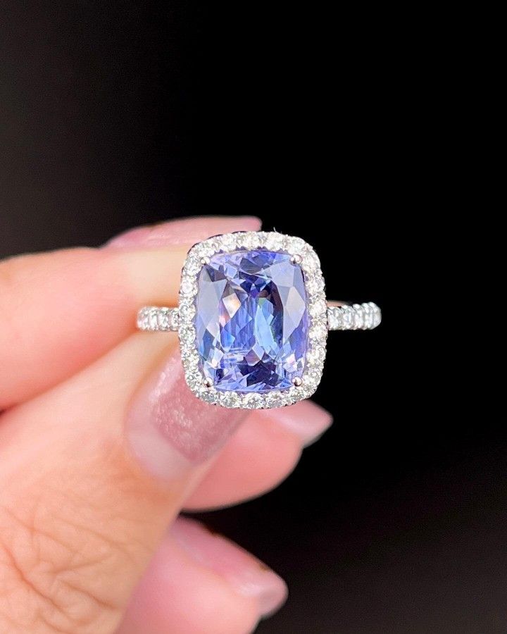 a woman's hand holding an engagement ring with a blue stone in the center