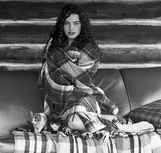 a black and white photo of a woman sitting on a couch with a cat in her lap