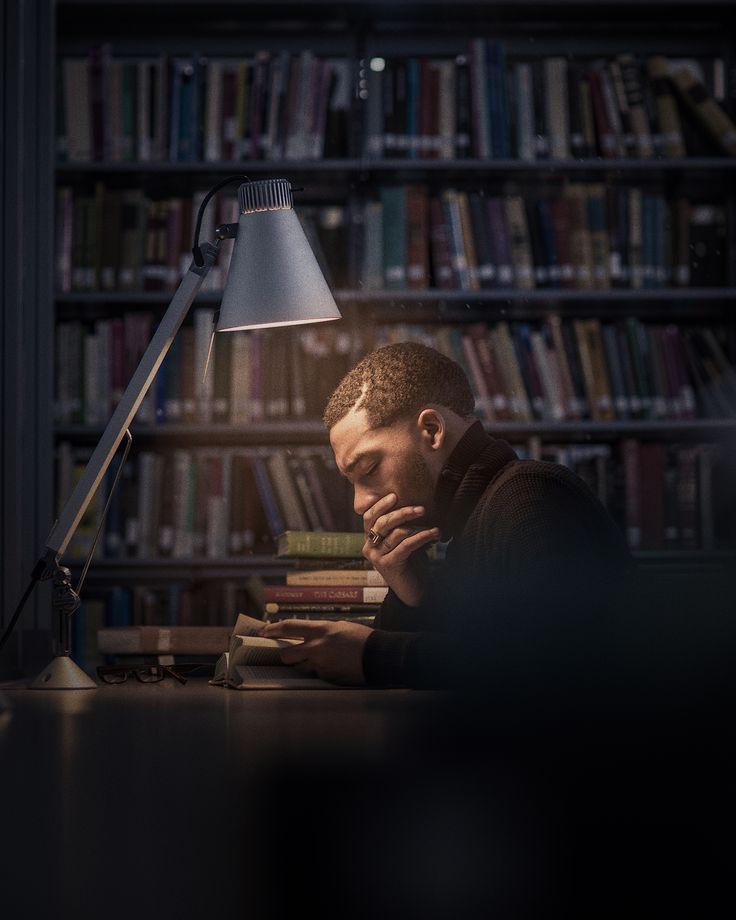 a man sitting at a desk in front of a book shelf with books on it