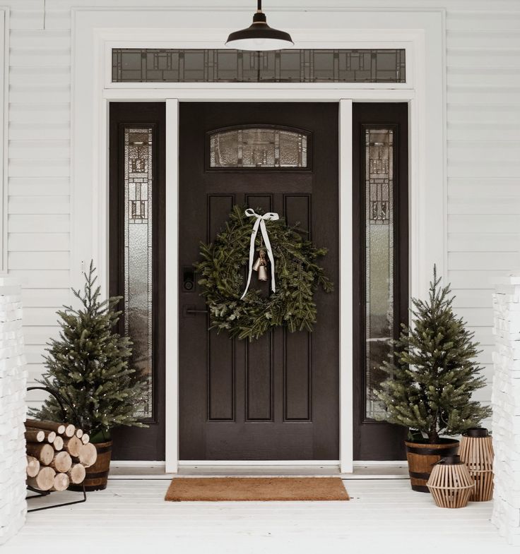 the front door is decorated with wreaths and evergreen trees