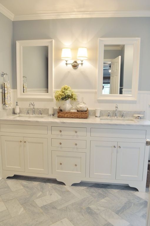 a large bathroom with two sinks, mirrors and lights on the wall above them is shown