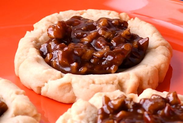 three cookies with caramel toppings on an orange plate