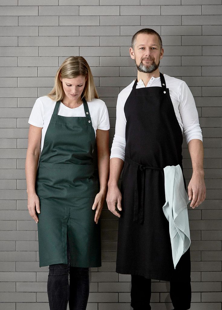 a man and woman standing next to each other in front of a gray brick wall