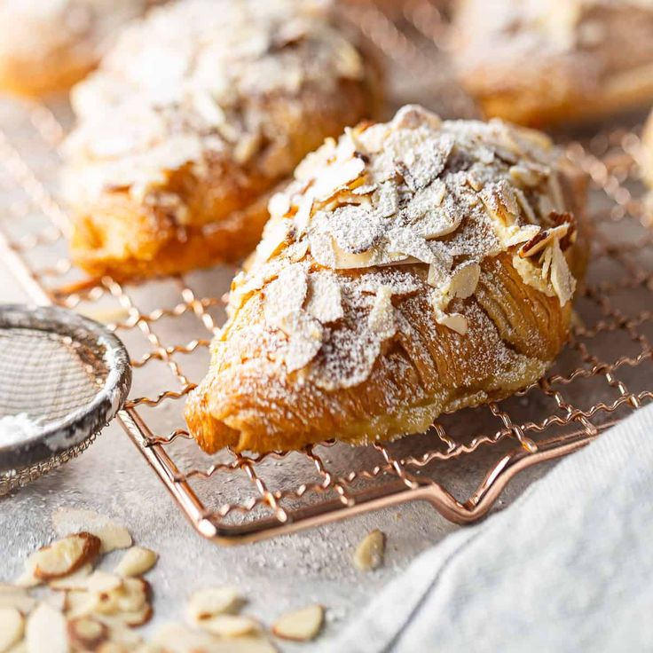 several pastries on a cooling rack with a scoop of powdered sugar next to them