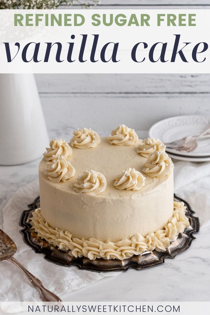 a white cake sitting on top of a table next to a vase filled with flowers