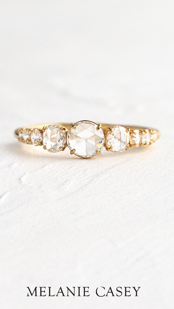 the three stone ring is shown in yellow gold with diamonds on each side and an oval shaped