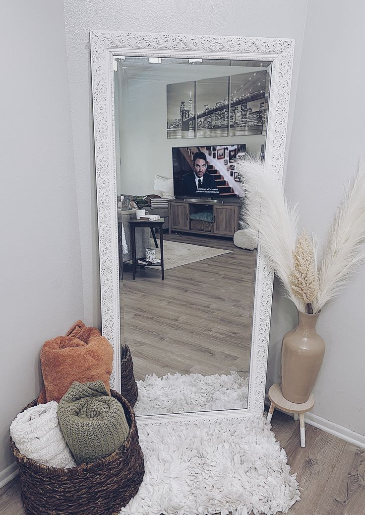 a mirror sitting on top of a wooden floor next to a basket filled with pillows