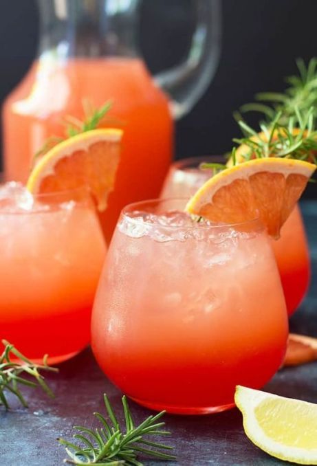 two glasses filled with watermelon lemonade and garnished with rosemary