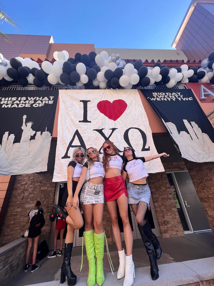 three girls posing in front of an i love axo banner