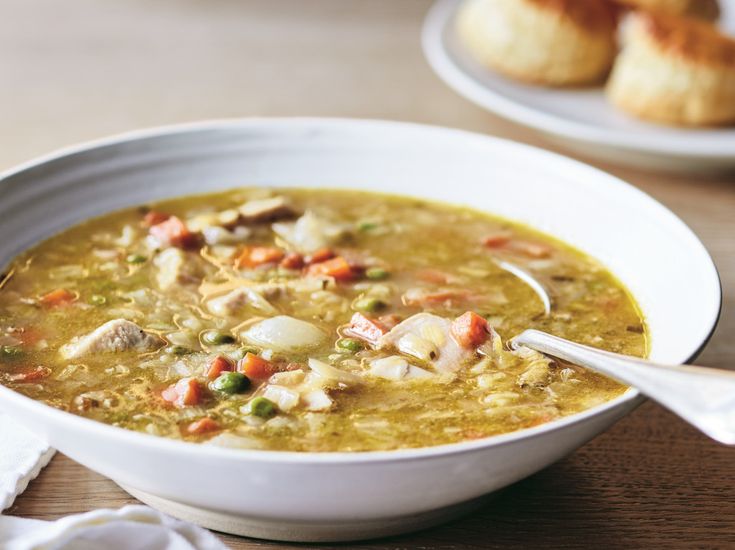 a white bowl filled with soup next to rolls