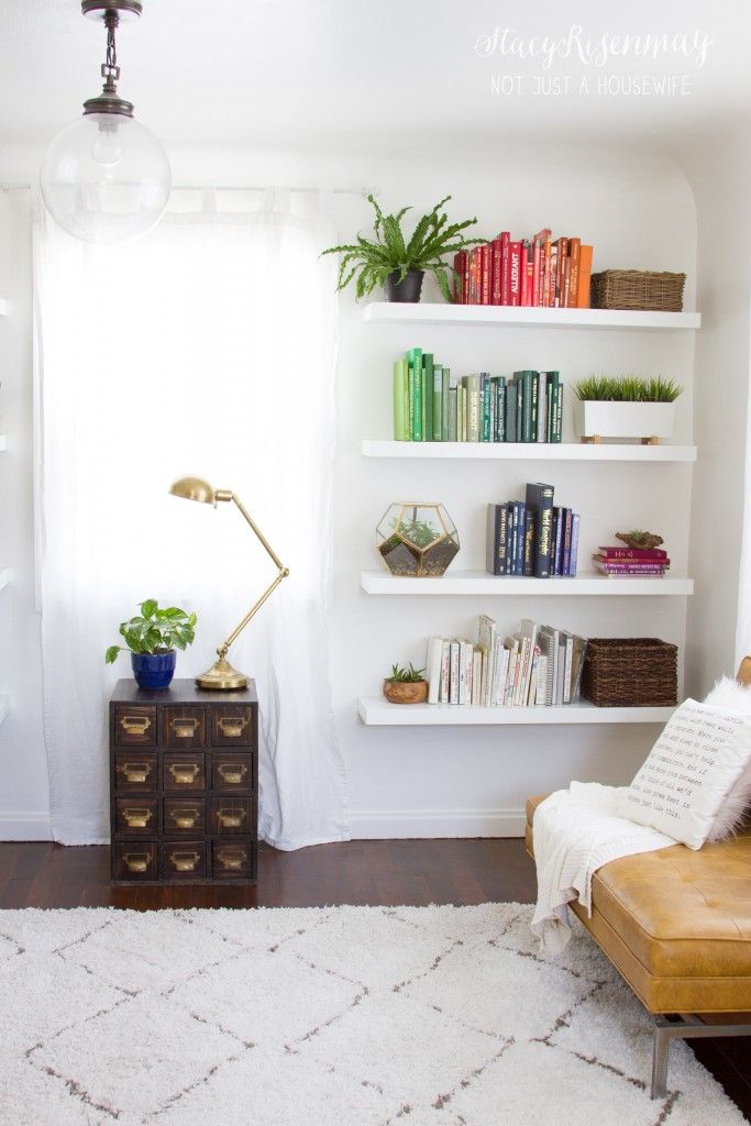 a living room filled with furniture and bookshelves next to a white rug on top of a hard wood floor