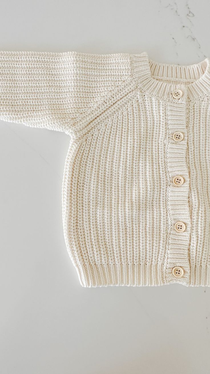 Unlock a world of warmth and comfort with this cozy Chunky Knit Cardigan! Perfect for a chilly day, it'll keep your little one snug and stylish with its traditional knit design, front buttons for convenience, and snug fit. Wrap your little one in chunky knit cuteness! Pair this cardigan with our 'Chunky Knit Beanie' Cute Cream Cotton Cardigan, Cream Ribbed Knit Cardigan, Cozy Cream Sweater Coat With Buttons, Soft Knit Sweater For Playtime In Fall, Cozy Winter Sweater For Playtime, Cream Cotton Sweater With Button Closure, White Knit Sweater For Playtime, Cream Cotton Cardigan With Soft Knit, Winter Cotton Cardigan For Playtime