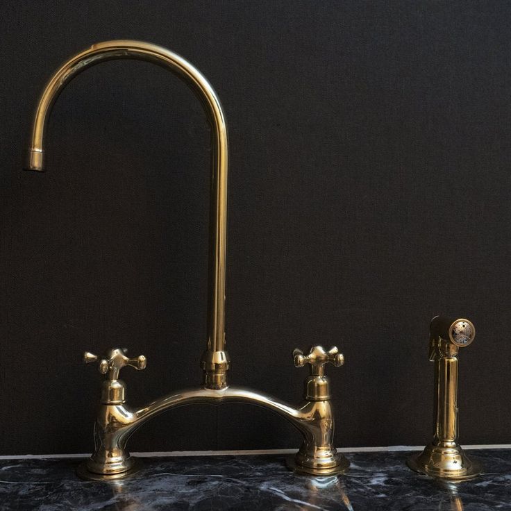 two brass faucets on a marble countertop in a black room with dark walls