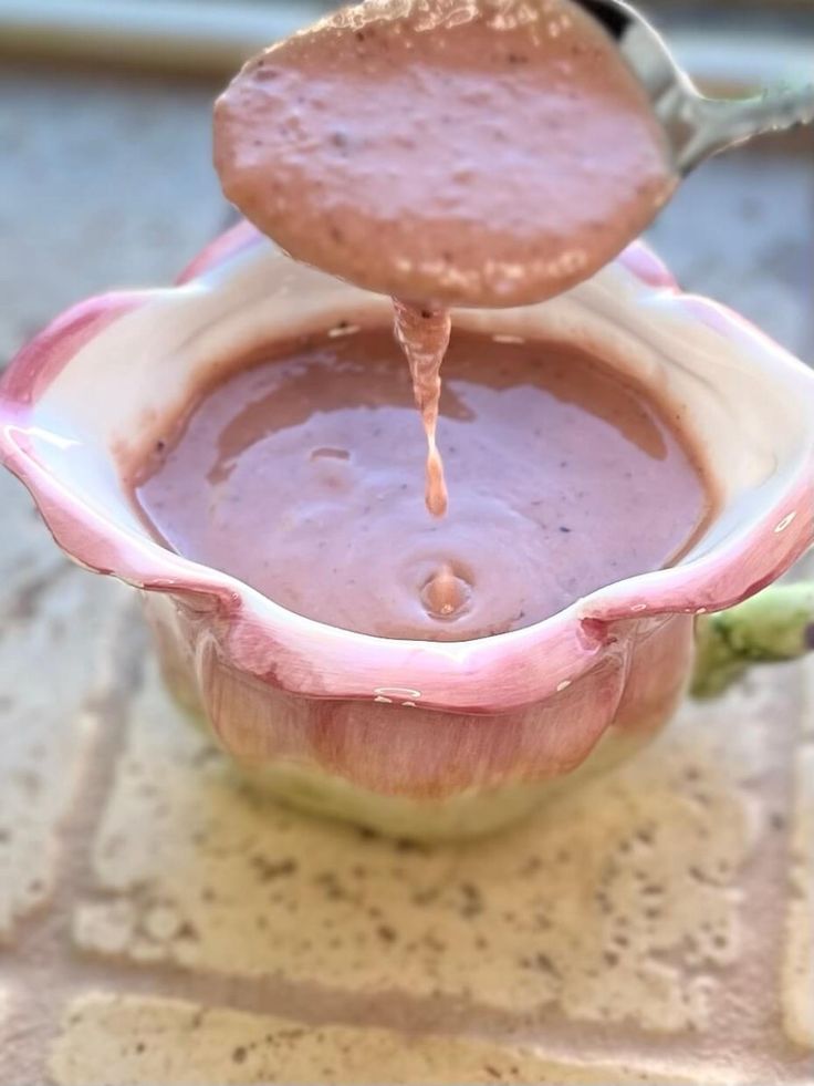 a spoon is pouring sauce into a bowl