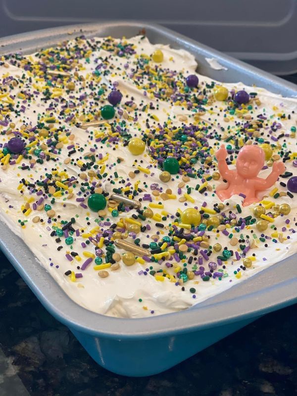 a cake with white frosting and sprinkles in a blue pan on a counter