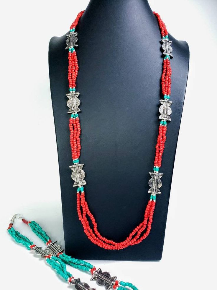 Add color and pizzazz to any outfit with this beautiful hand crafted Tibetan coral color multi strand bead necklace with silver tone amulets. The faux turquoise accents makes the amulets pop! A simple but very striking necklace! Perfect for a beach vacation with a carefree white dress or in the city to dress up jeans. Makes a beautiful gift! Twist the necklace for a totally different look! Excellent quality and craftsmanship. - 3 strands of irregular beads - bright red/orange color - silvertone Red Multi-strand Hand-strung Necklace, Unique Red Multi-strand Beaded Necklaces, Red Hand-strung Multi-strand Jewelry, Unique Red Multi-strand Beaded Necklace, Handmade Multi-strand Red Coral Jewelry, Unique Red Multi-strand Jewelry, Traditional Multi-strand Red Coral Necklaces, Traditional Multi-strand Red Coral Necklace, Artisan Multi-strand Red Necklaces