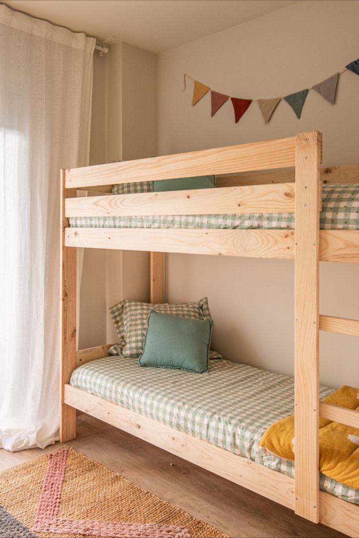 the bunk beds are made from wood and have checkered sheets on them, along with pillows