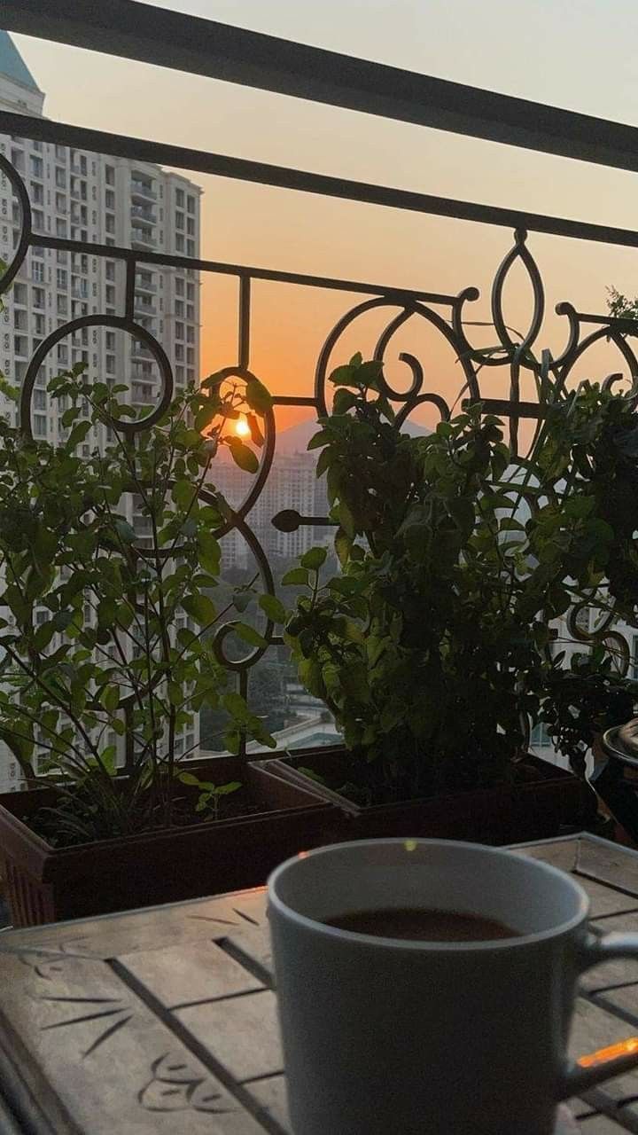 a cup of coffee sitting on top of a wooden table next to a potted plant