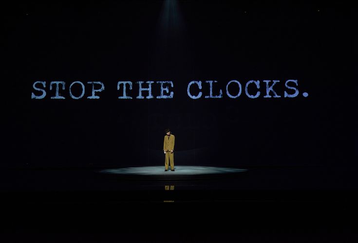 a man standing on top of a stage with the words stop the clocks