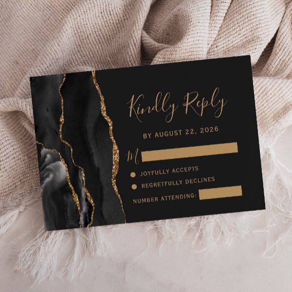 a black and gold foiled business card sitting on top of a bed