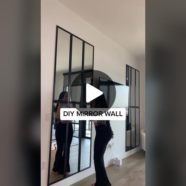 a woman standing in front of a mirror with the words diy mirror wall on it