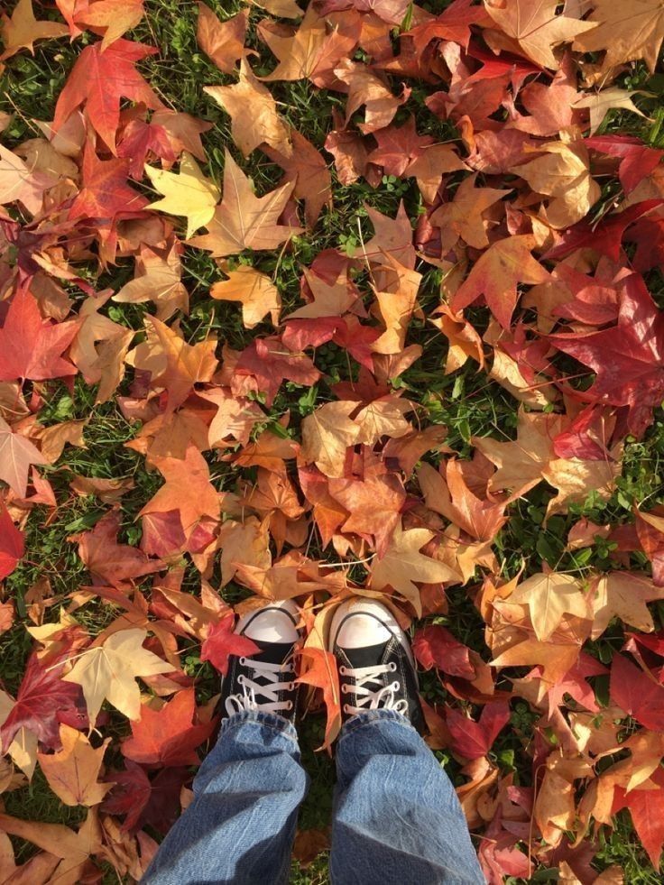 a person standing in front of a pile of leaves on the ground with their feet up