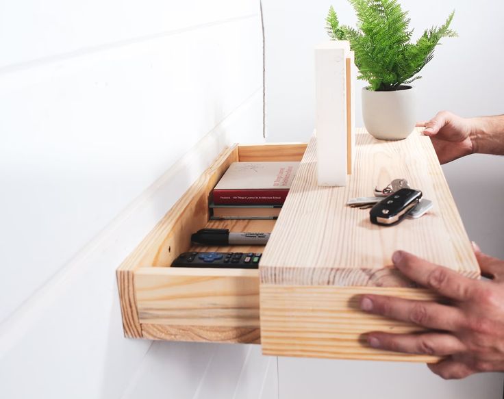 a person holding a wooden drawer with keys and other items in it on the table