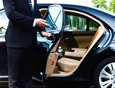 a man in a tuxedo getting out of a car with his hand on the door handle