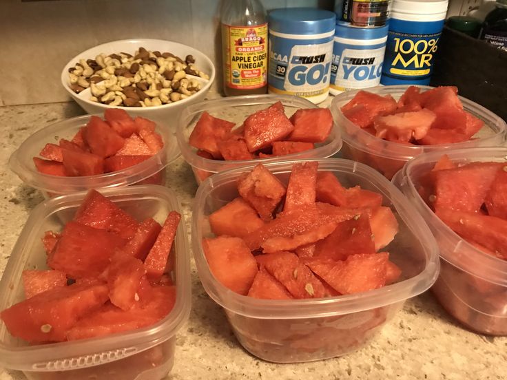 several plastic containers filled with watermelon sitting on top of a counter next to nuts