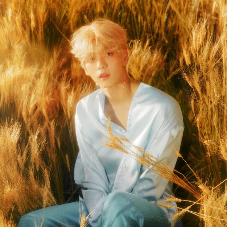 a young man sitting in the middle of tall grass